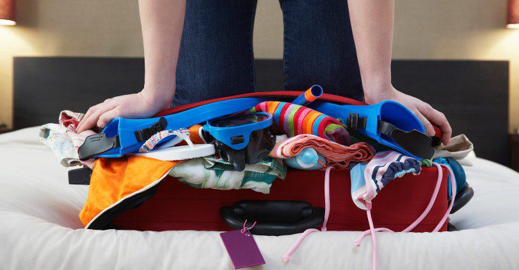 Jeune femme en train de fermer sa valise (Istock)