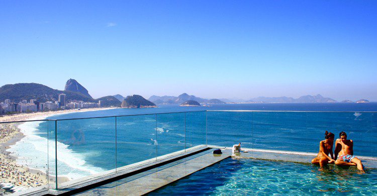 Couple qui se rapproche dans une piscine avec l'océan en fond.