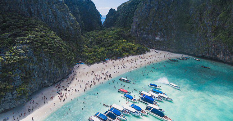 Vue aérienne de Maya Bay où l'on constate une forte affluence et voit de nombreux bateaux dans les eaux 