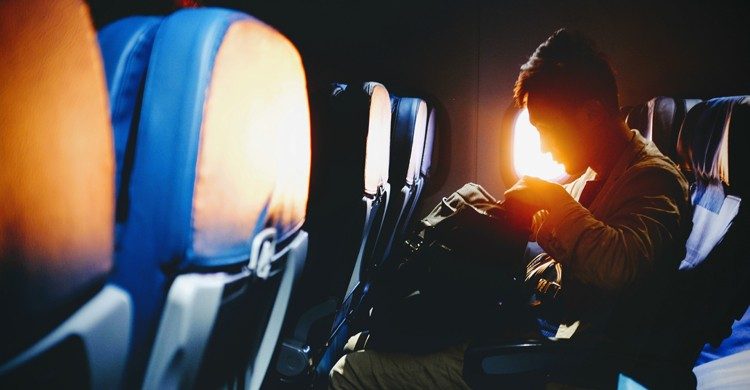 Homme dans un avion qui regarde le contenu de son bagage à main